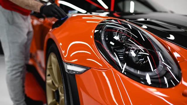 Coating being wiped onto the front of an orange Porsche 911