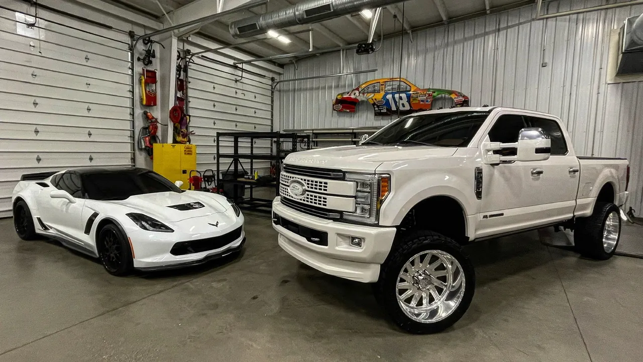 A white Corvette and a lifted Ford Super Duty inside the shop