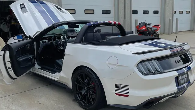 White Mustang GT convertible with blue stripes, doors open